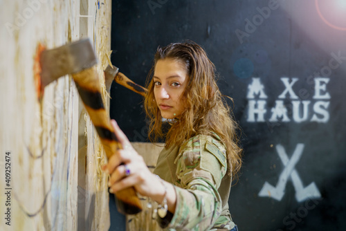 woman retrieving two axes from targets with graffiti