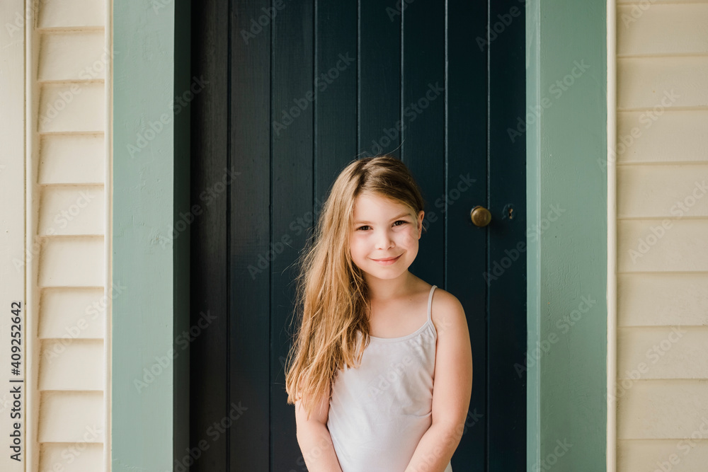 Smiling young girl standing outside in front of a door Smiling young girl standing outside in front of a door