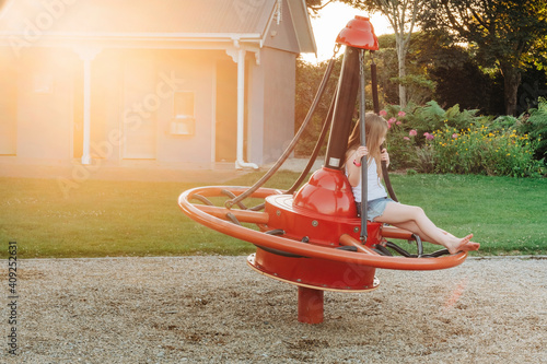 Young girl sitting on playground equipment at the park