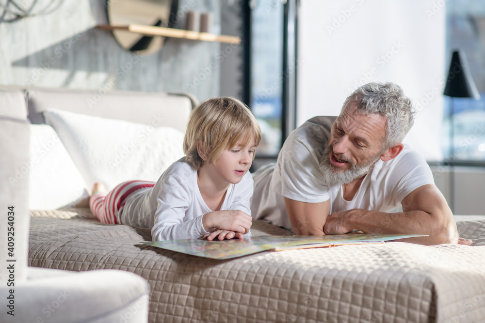 Gray-haired man reading children book and child Gray-haired man reading children book and child