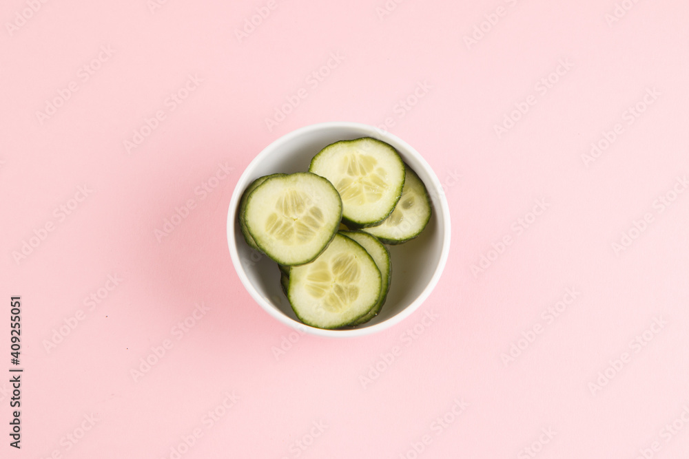 Cucumber slices in a bowl with a pink background Cucumber slices in a bowl with a pink background