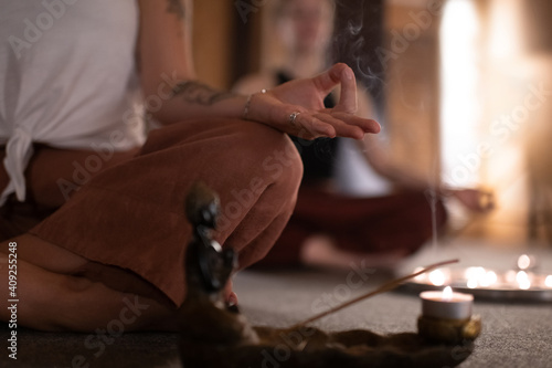 Anonymous female meditating near incense smoke