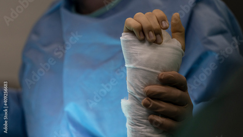 A surgeon holds the wrist of an operated patient in the operating room