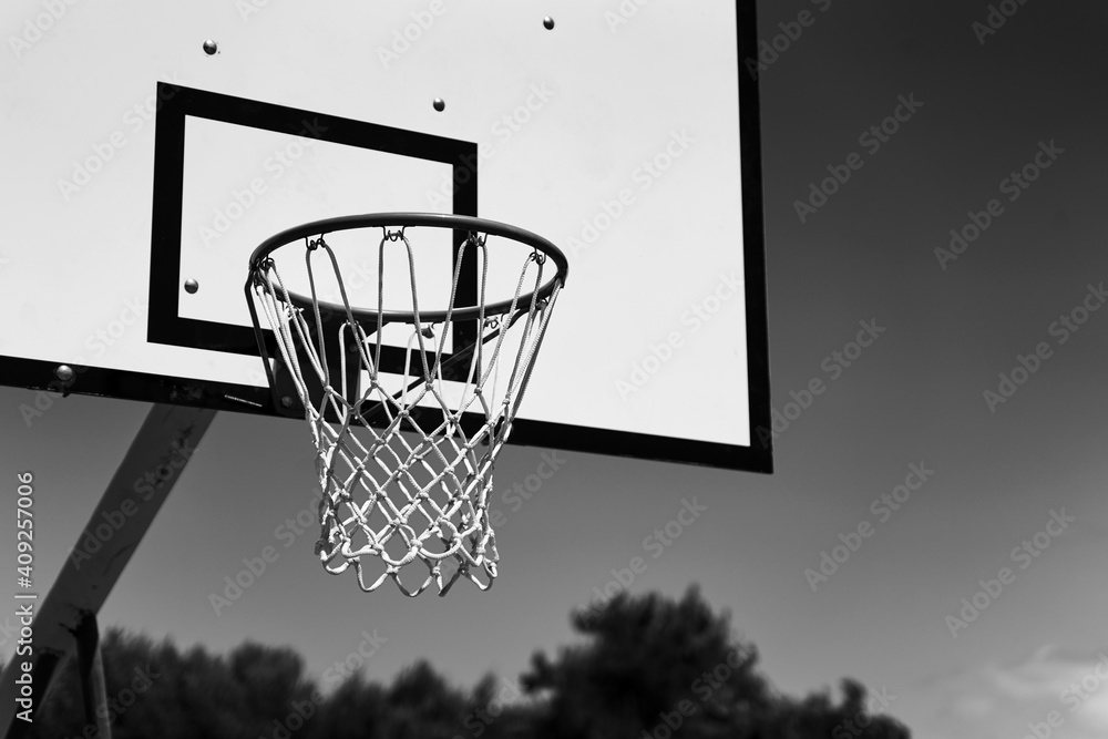 Outdoor basketball hoop or goal on sky background in black and white.