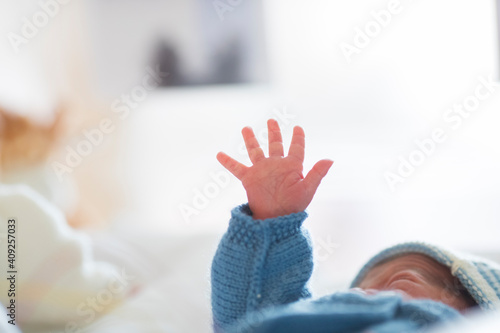 a newborn in his cradle raises his hand photo