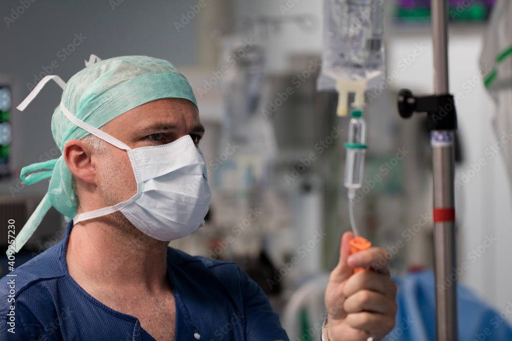 a doctor adjusts a dropper during surgery in the operating room a doctor adjusts a dropper during surgery in the operating room