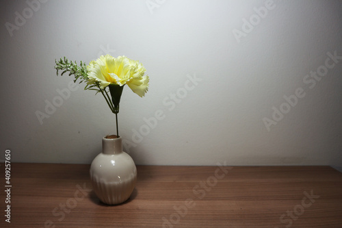 Yellow carnation flowers in vintage vase on wooden table, floor, gray cement wall Stylish stock image format for banner templates, text artwork, quotes, fonts, festivals