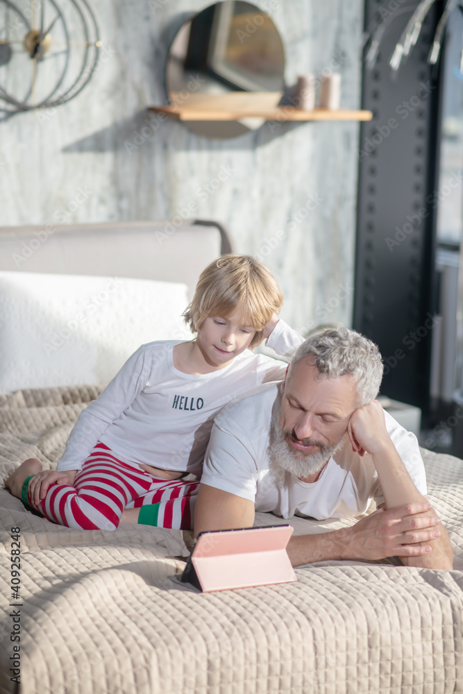 Obraz premium Baby sitting dad lying looking tablet