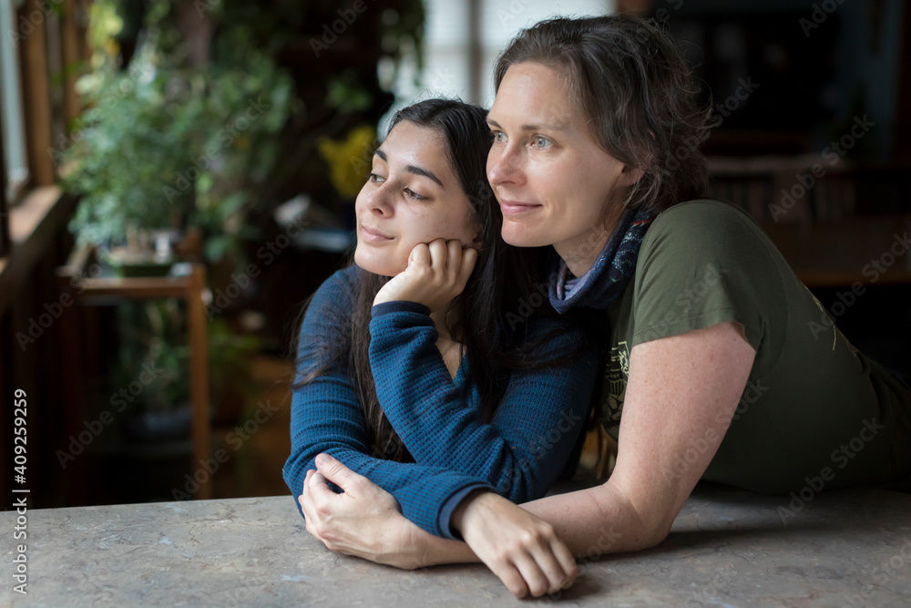 Mother with arms around pretty teen daughter looking off camera Mother with arms around pretty teen daughter looking off camera