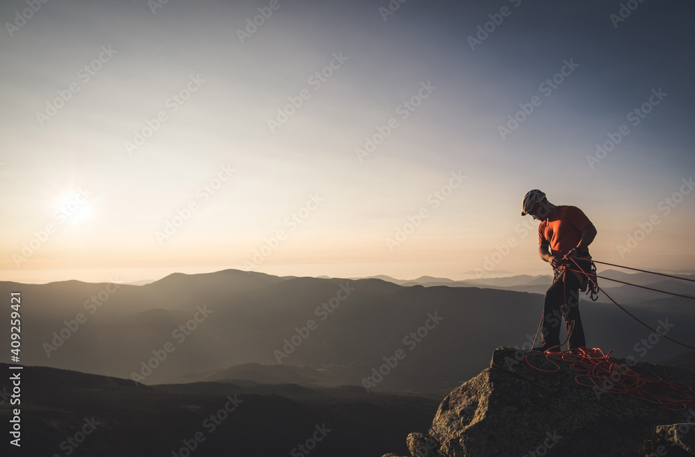 Man belaying with climbng ropes at sunrise in mountains Man belaying with climbng ropes at sunrise in mountains