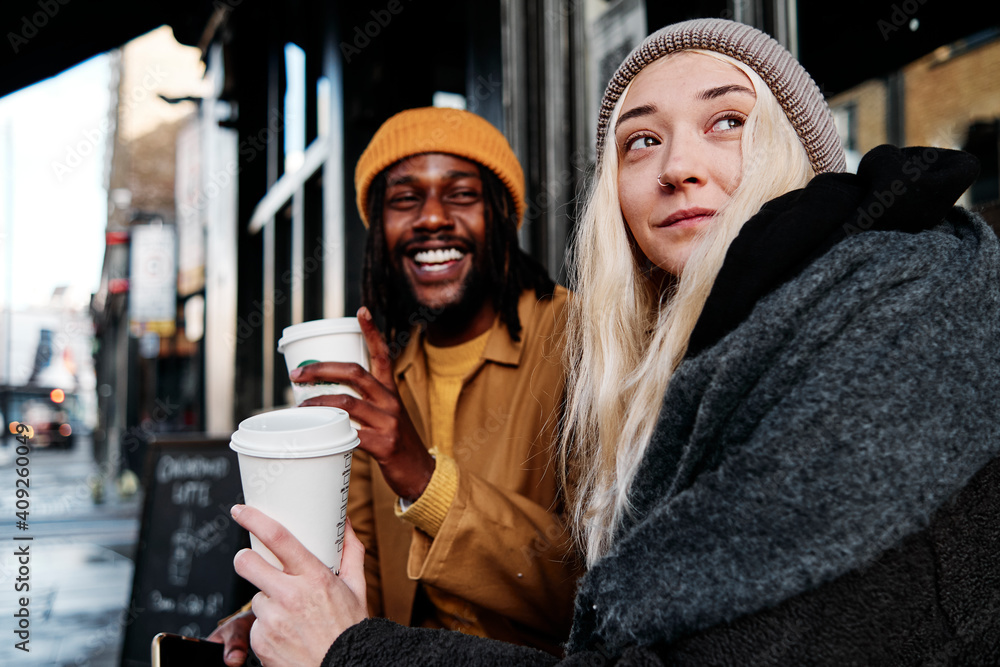 Multiracial Couple Sitting Outdoors Laughing While Drinking Coffee Biracial Lovers On A Date