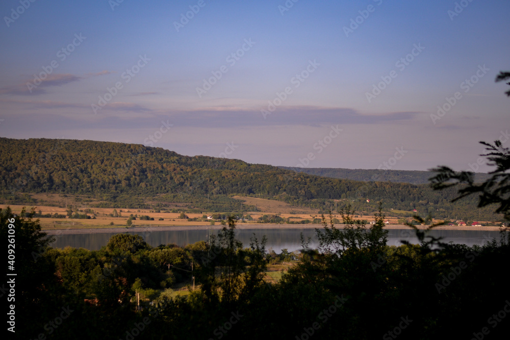 spring landscape with forest near the lake at sunset. cultivated fields