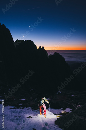 Young man hiking to summit before sunrise against mountains and crescent moon, Gredos, Spain photo