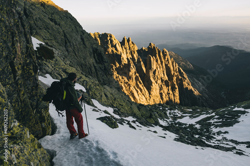 Young man assessing hike downhill situation during sunset at Gredos, Avila, Spain