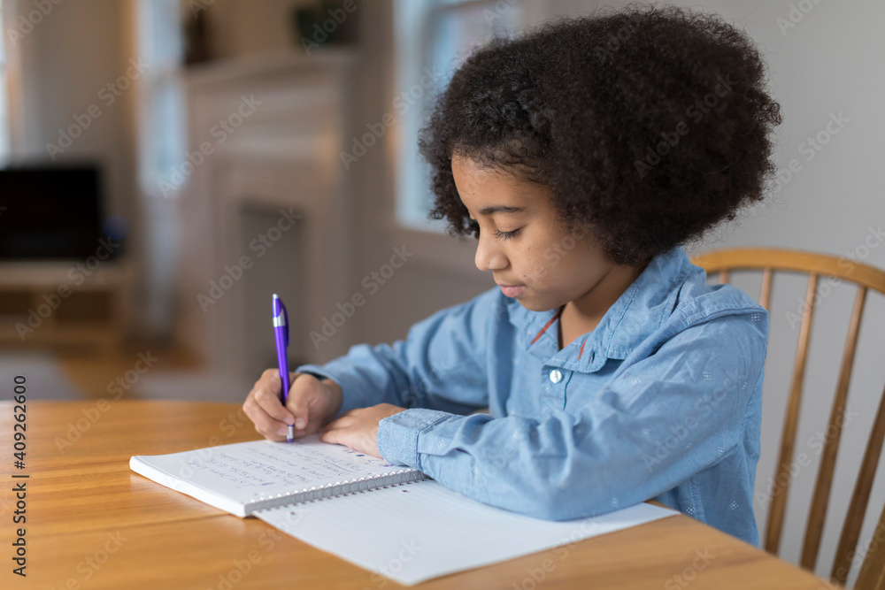 Ten year-old bi-racial girl doing homework at table Ten year-old bi-racial girl doing homework at table