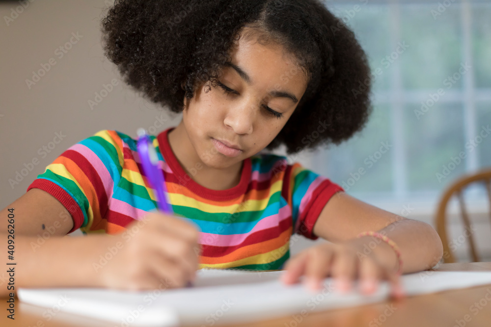 Ten year-old bi-racial girl doing homework at table Ten year-old bi-racial girl doing homework at table
