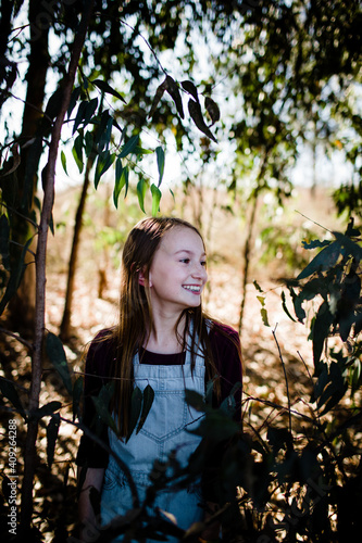 Young Girl Standing in Park with Leaves in Foreground photo