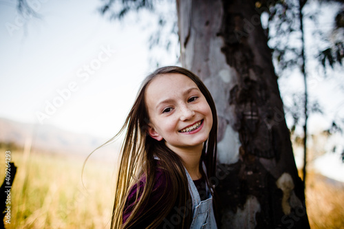 Young Girl Smiling for Camera Next to Tree photo