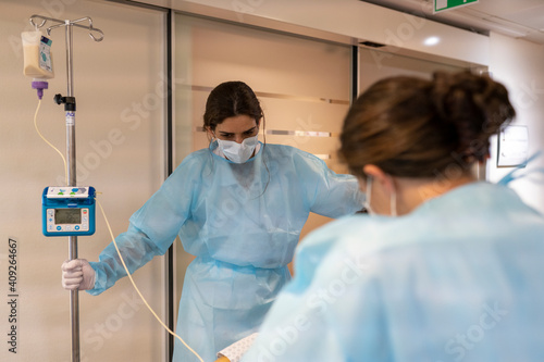 two nurses help a patient walk in a hallway photo