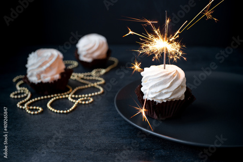 Delicious cupcakes with sparkler on dark background photo