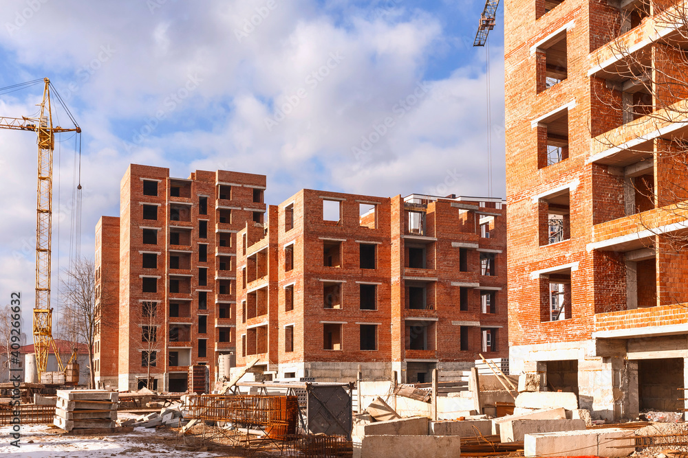 Multi-storey buildings under construction. Construction site with a tower crane and concrete blocks Multi-storey buildings under construction. Construction site with a tower crane and concrete blocks