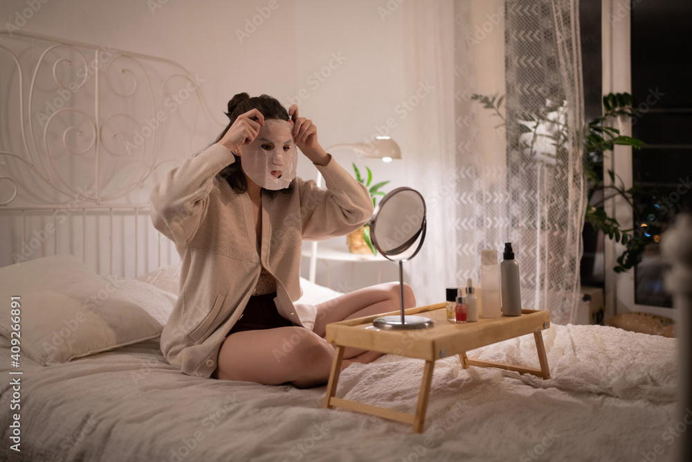 Young woman applying sheet mask Young woman applying sheet mask