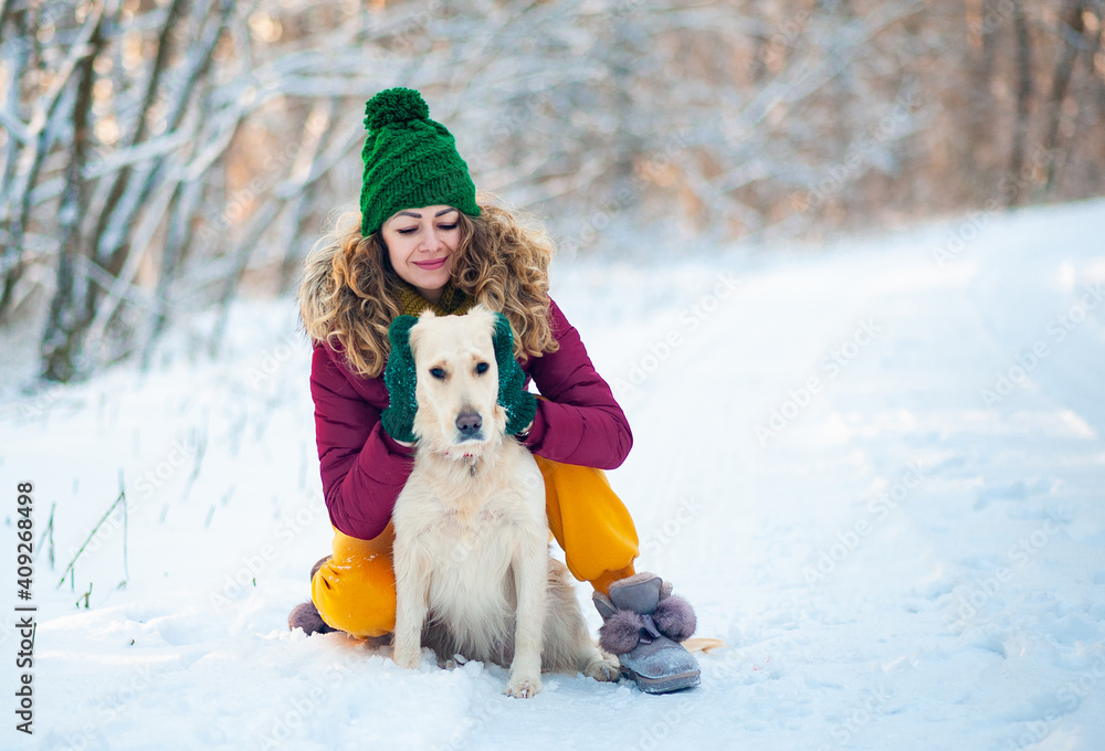 Smiling woman hugging her pet dog golden retriever near face. Golden retriever playing with a woman walking outdoors winter day, warm clothing. love and care for the pet. Smiling woman hugging her pet dog golden retriever near face. Golden retriever playing with a woman walking outdoors winter day, warm clothing. love and care for the pet.