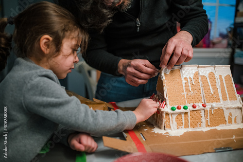 Dad and daughter building gingerbread house in kitchen