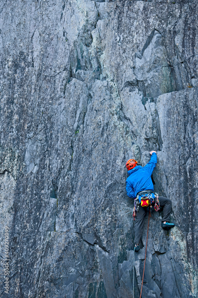 man climbing up steep rock face at Slate quarry in North Wales man climbing up steep rock face at Slate quarry in North Wales