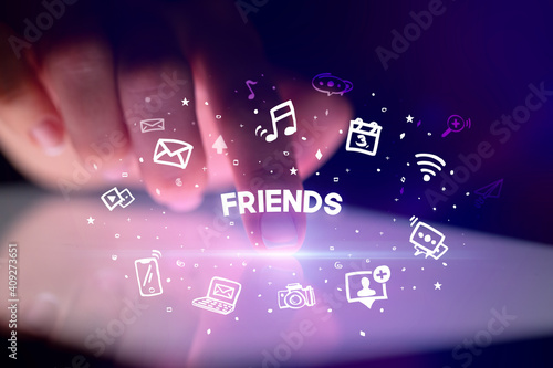 Finger touching tablet with drawn social media icons and FRIENDS inscription, social networking concept