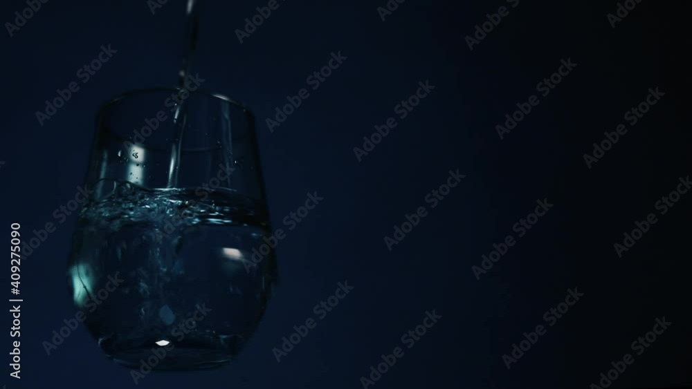A glass full of a fresh water isolated on a blue background with copy space for text A glass full of a fresh water isolated on a blue background with copy space for text