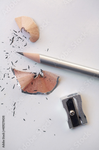 Closeup of metal pencil sharpener with silver pencil on white table