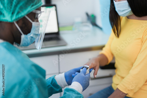 Photos African doctor using pulse oximeter on young woman patient - Measuring oxygen sa