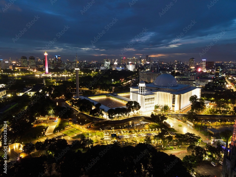Obraz premium Aerial view of Istiqlal Mosque. It is the largest mosque in Southeast Asia and noise cloud at night with Jakarta cityscape. JAKARTA - Indonesia. January 30, 2021