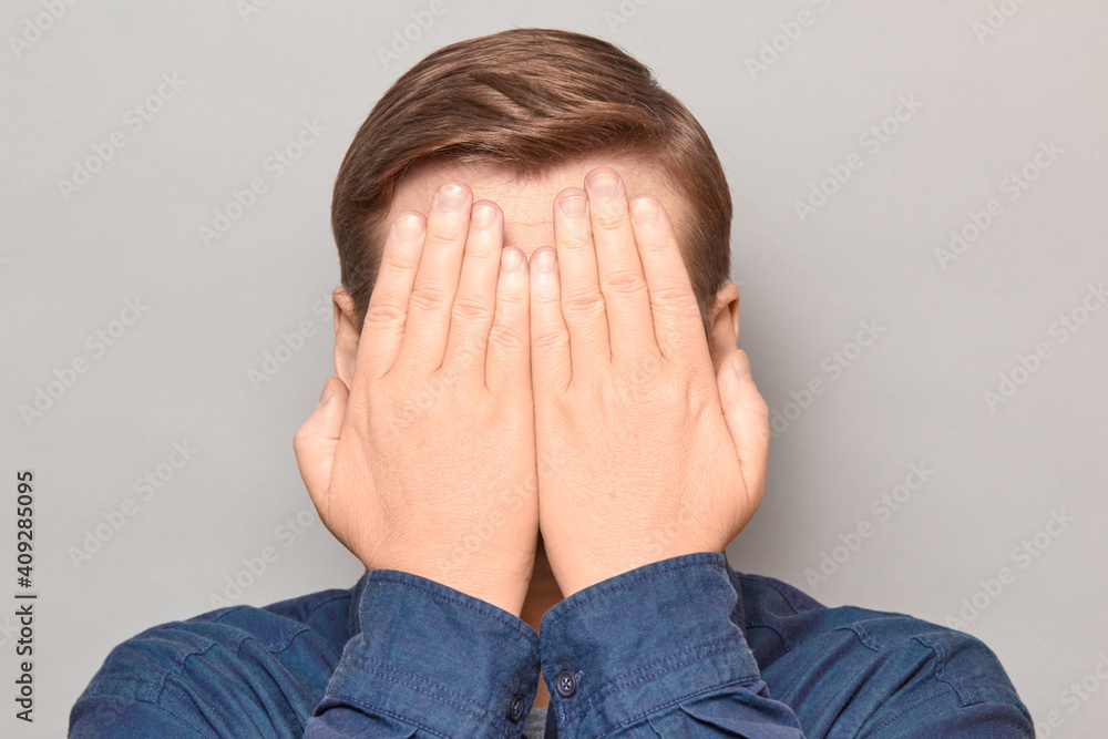 Portrait of blond man covering his face with hands Portrait of blond man covering his face with hands