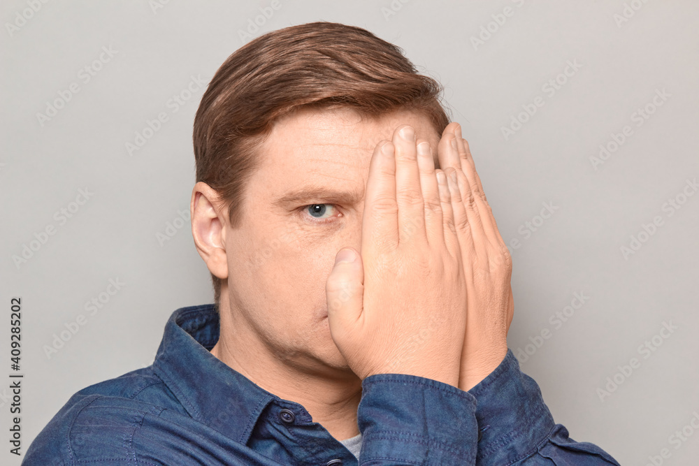 Portrait of mature man looking with one eye at something interesting Portrait of mature man looking with one eye at something interesting
