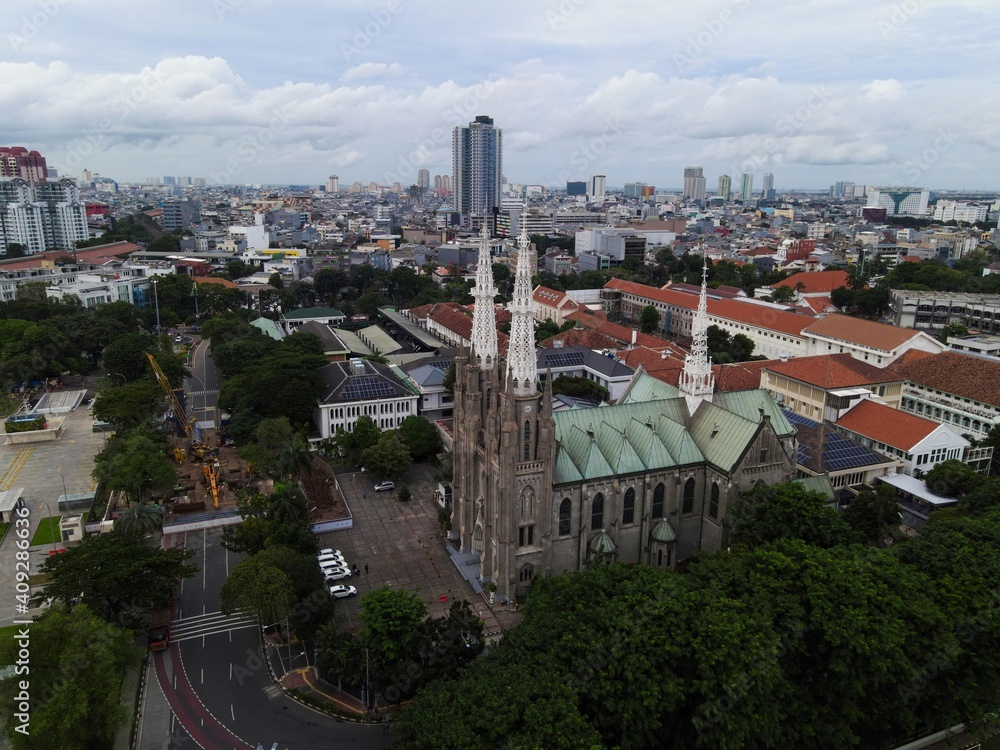 Aerial view of Jakarta cathedral. It is the largest mosque in Southeast Asia and noise cloud with Jakarta cityscape. JAKARTA - Indonesia. January 30, 2021