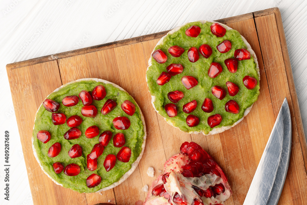 Close up rice cakes with avocado mash and pomegranate seeds top view Close up rice cakes with avocado mash and pomegranate seeds top view