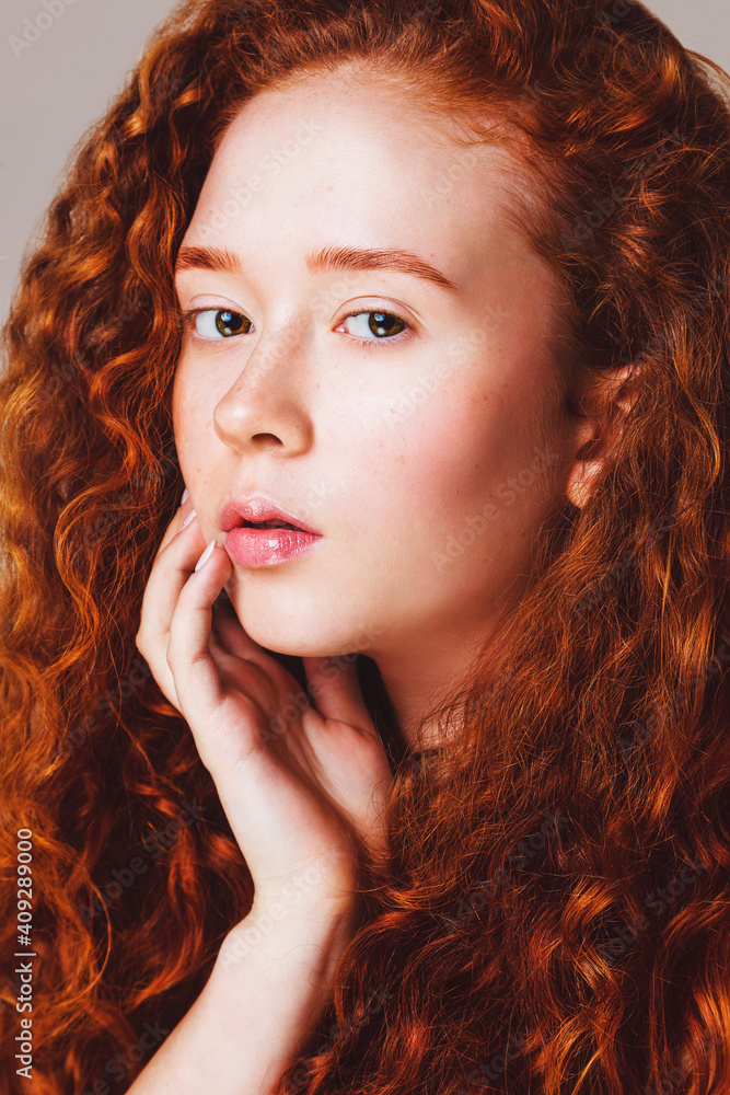 close-up portrait of a red-haired girl with brown eyes and long curly hair and small freckles without makeup. Studio shot close-up portrait of a red-haired girl with brown eyes and long curly hair and small freckles without makeup. Studio shot
