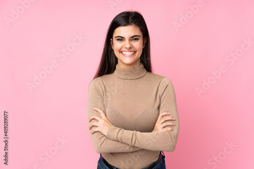 Young woman over isolated pink background keeping the arms crossed in frontal position