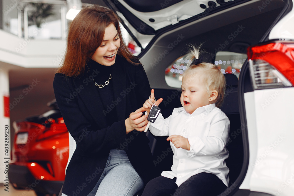 Fototapeta premium Family in a car salon. Mother with daughter. Lady in a black jacket.