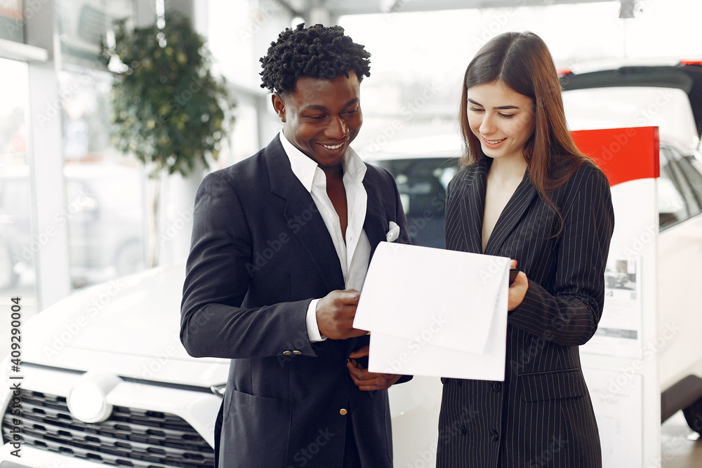 Man buying the car. Assistant helps to choose a car. Businessman in a car salon. Black male in a suit. Man buying the car. Assistant helps to choose a car. Businessman in a car salon. Black male in a suit.