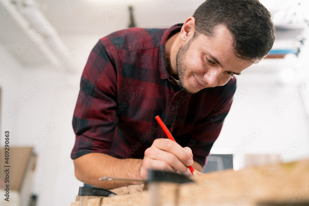Exact measured. Close-up of young male carpenter making measurements on the wooden plank Exact measured. Close-up of young male carpenter making measurements on the wooden plank
