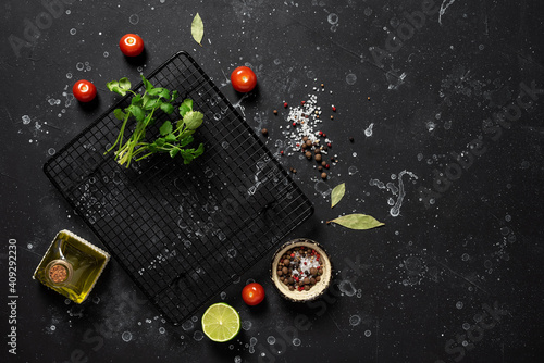 Black stone background with food, spices, vegetables, greens and oil. Ingredients for cooking. Top view, copy space.