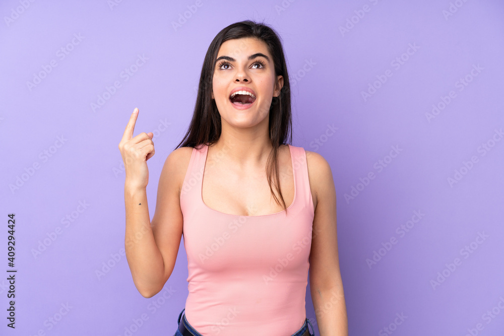 Young woman over isolated purple background pointing up and surprised Young woman over isolated purple background pointing up and surprised