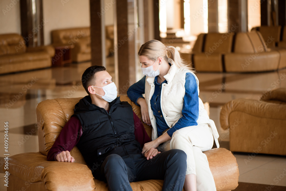 Young couple wearing a mask in an airport lounge. Coronavirus influenza virus travel concept. Young couple wearing a mask in an airport lounge. Coronavirus influenza virus travel concept.