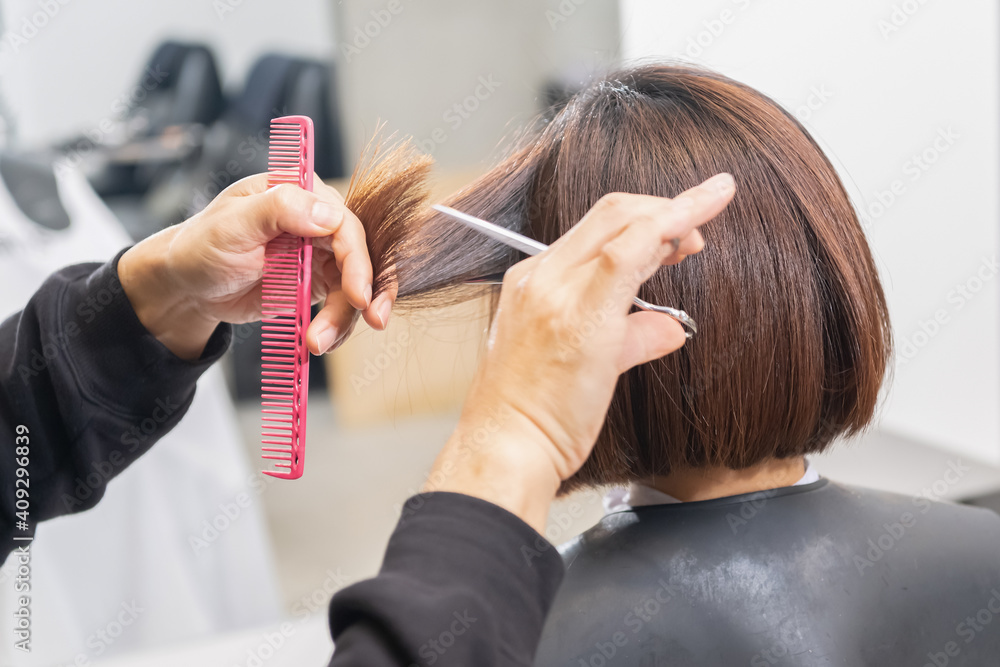 Naklejka premium ヘアサロンで髪の毛をカットする美容師の手元