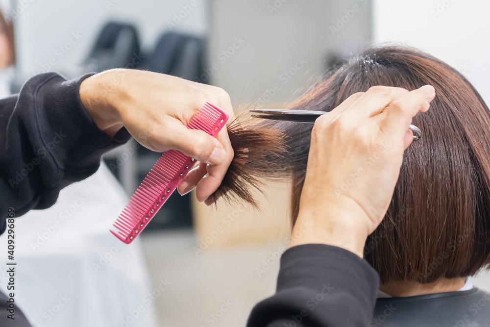 Naklejka premium ヘアサロンで髪の毛をカットする美容師の手元