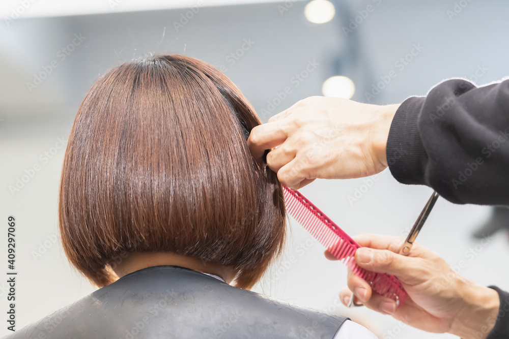 Fototapeta premium ヘアサロンで髪の毛をカットする美容師の手元