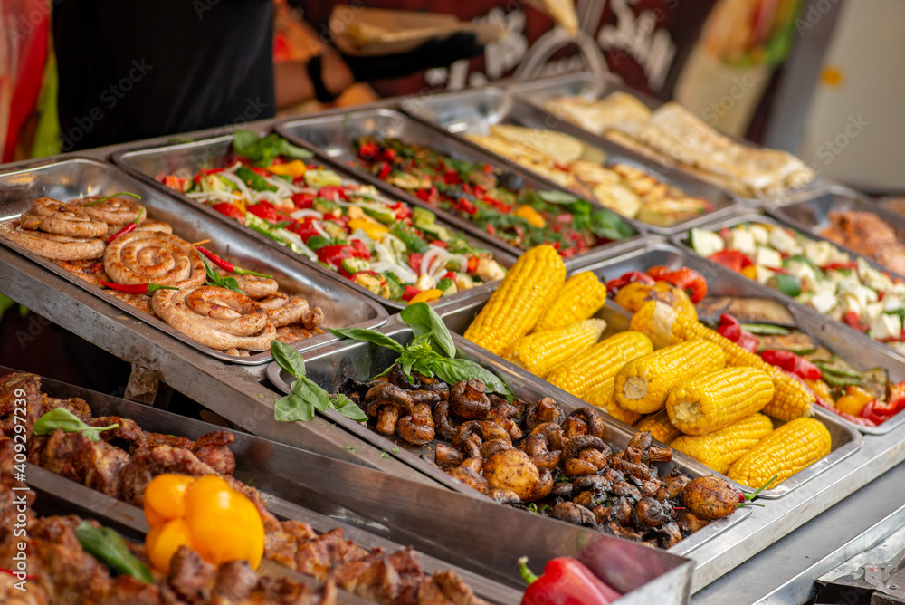 Fototapeta premium Trays filled with food at the food court. Street food. Grilled vegetables and meat.